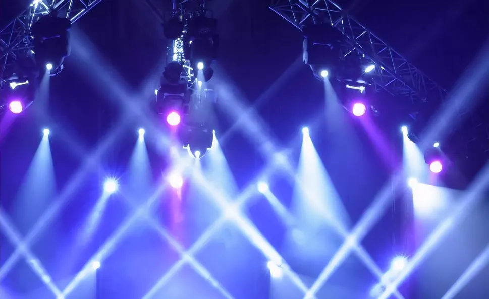 Stage lighting beams crossing above an empty stage